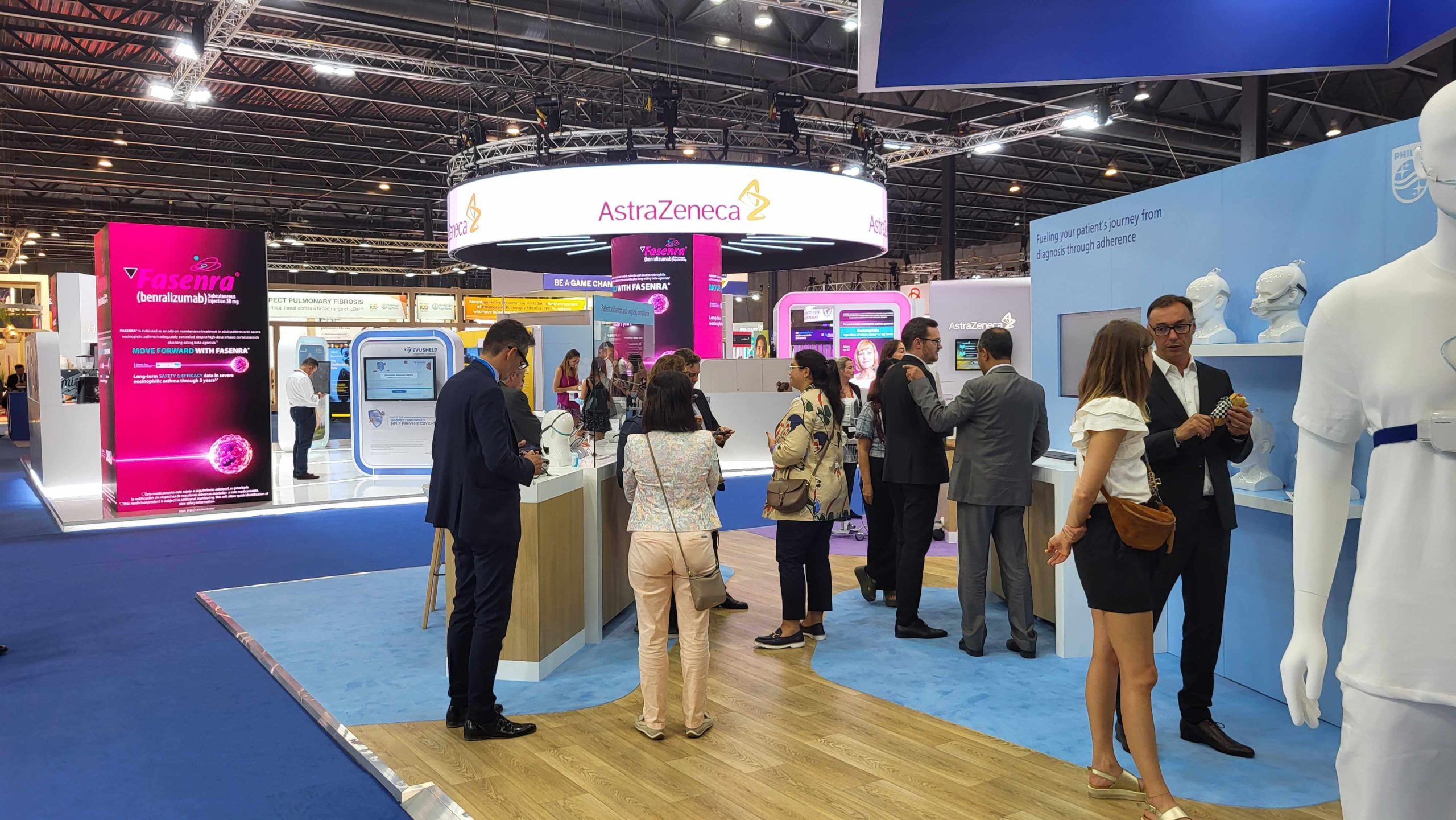 AstraZeneca booth with multiple people watching demos and talking to staff