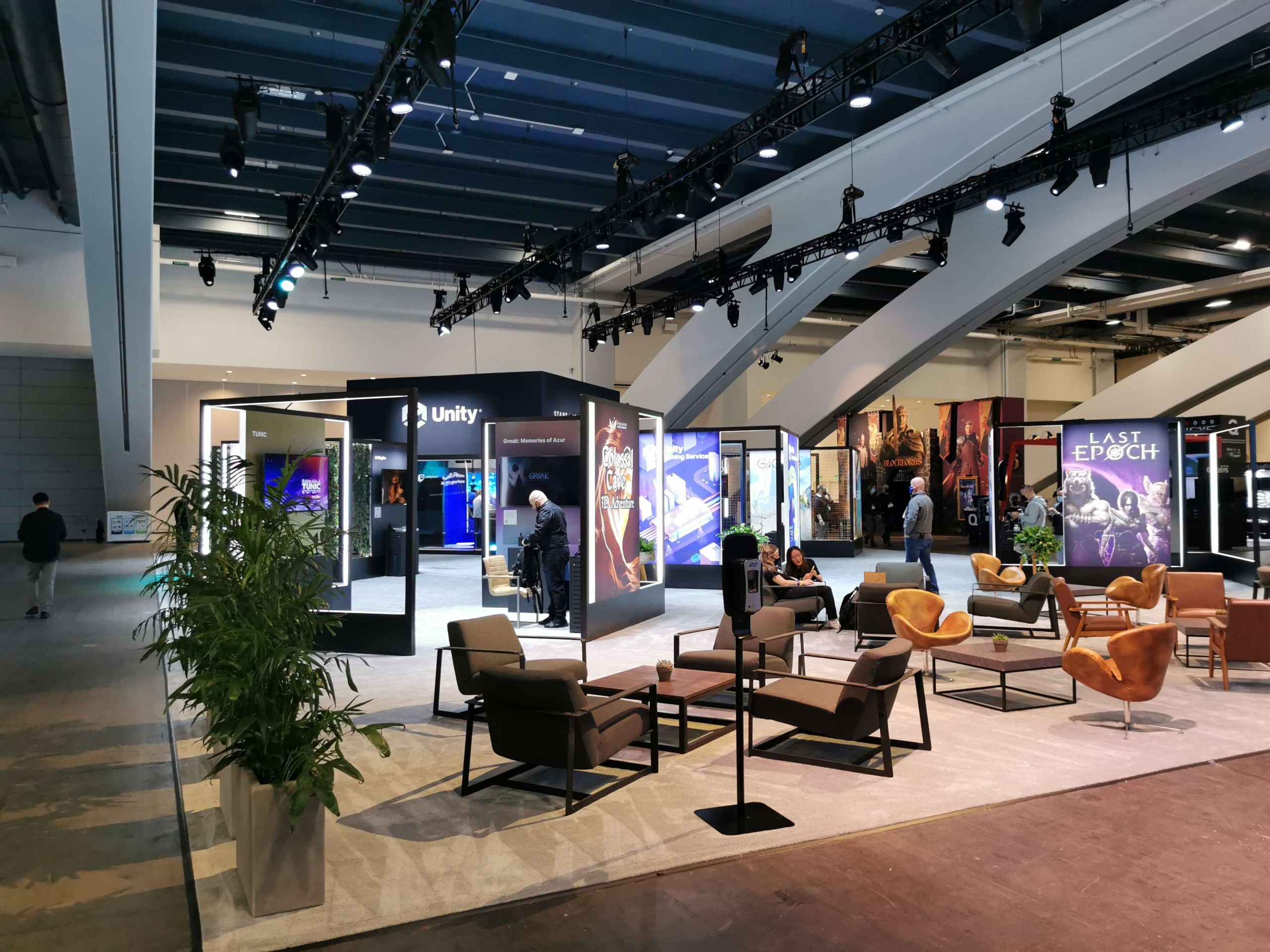 Unity display booth at a business expo, with arm chairs and social area